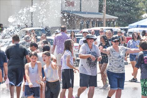 Good Old Days Parade spectators are sprayed down on a hot day by St. Ignatius fire trucks.