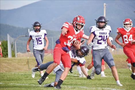 An Arlee Warrior football player advances the ball down the fall before being tackled by a Charlo Viking.