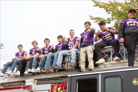  Football players point and wave while riding on the top of a fire truck during the homecoming parade. 