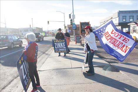 Local citizens hold signs and wave flags in downtown Polson on Friday, Oct. 18, encouraging passing motorists to vote for Ryan Zinke, and to vote Republican overall in the upcoming general election.