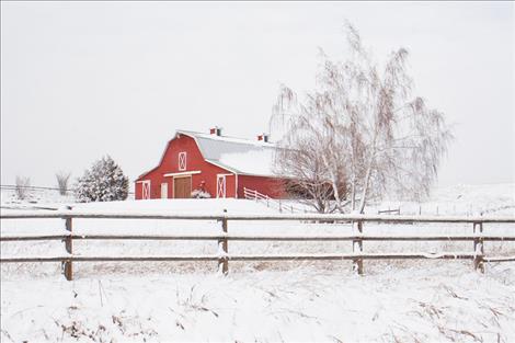 A red Mission Valley barn stands out in a snow covered landscape. Loopholes in tax codes aimed to encourage farming and ranching and preserve Montana's agricultural character have benefitted thousands of luxury real estate properties.