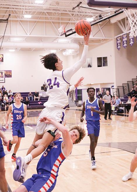 Polson boys basketball player Malakai Curley, drives to the basket, is blocked, scores and then makes a free throw.